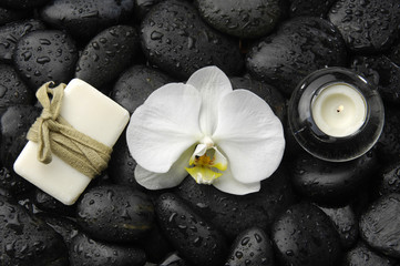 Fototapeta na wymiar White orchid and candle with soap on zen stones background