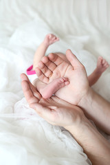 Obraz na płótnie Canvas Męskie ręce trzymając nogi dziecka