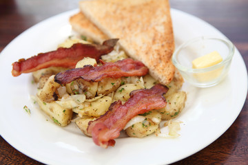 Breakfast of  bacon, toast and hash browns.