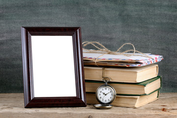 Photo frame and pile of old books on wooden table