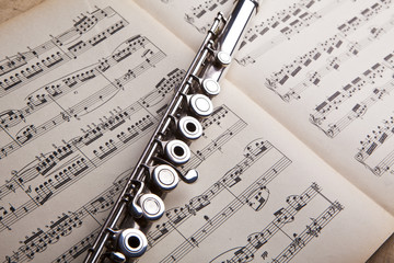 Silver flute on an ancient music score background