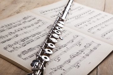 Silver flute on an ancient music score background