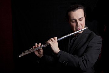 professional flutist musician playing flute on black background