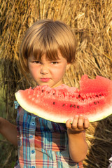 The small child outdoors eats water-melon