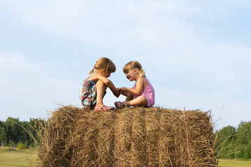 Naklejka na ściany i meble Two girls sit on haystack