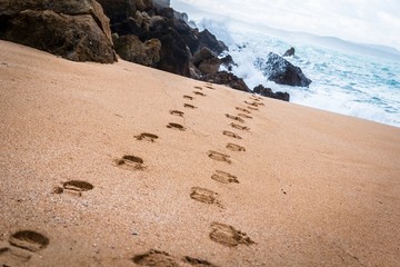 Footprints towards the sea in an empty beach