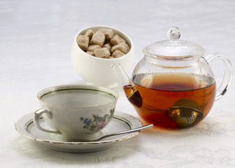 Teapot with tea, cup on a saucer and sugar bowl with brown and w