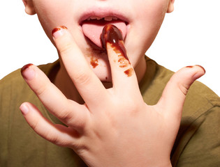Child licks a chocolate glaze with your finger
