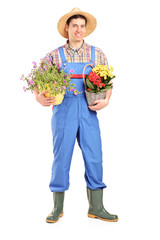 Full length portrait of a male gardener holding plants