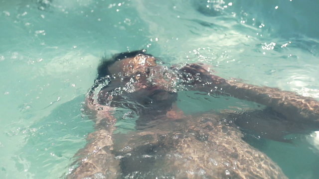 Man relaxing in swimming pool, slow motion shot at 120fps