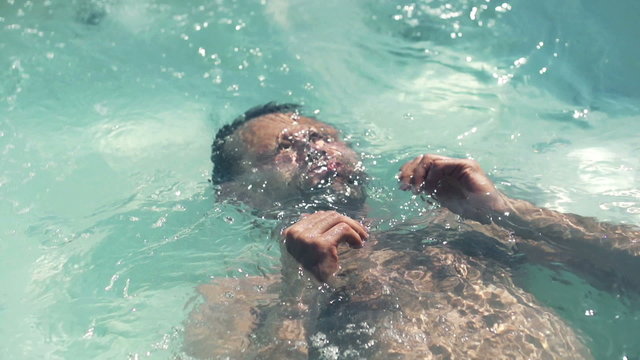 Man relaxing in swimming pool, slow motion shot at 240fps