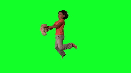 Side view of boy jumping up and catching teddy on green screen - Powered by Adobe