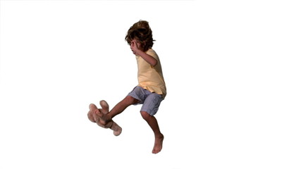 Little boy jumping up and kicking teddy on a white background - Powered by Adobe