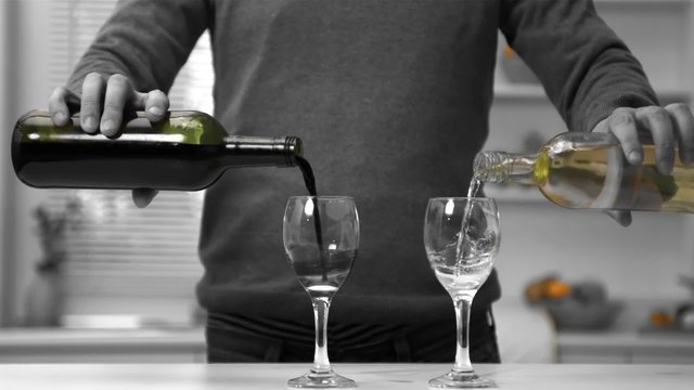 Man pouring red and white wine into two glasses
