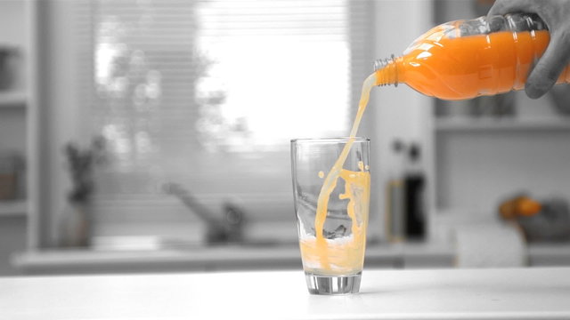 Mans hand pouring orange juice from a bottle into a glass