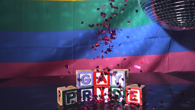 Heart confetti falling on blocks spelling gay pride