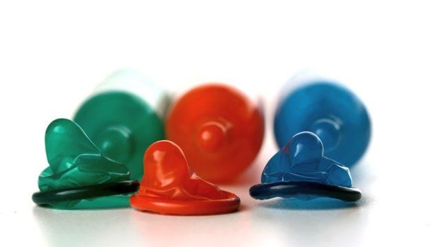 Colourful condoms falling in front of blown up condoms