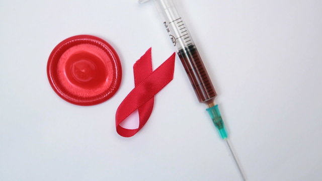 Red ribbon condom and syringe with blood sample