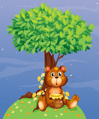 A bear holding a honey under a tree