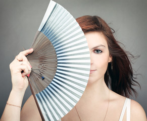 Portrait of mysterious woman hiding behind retro fan