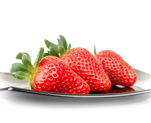 Three fresh strawberries on glass saucer isolated on white