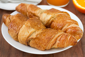 croissant on the plate with juice and orange
