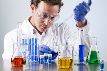 chemist working at a lab bench with various solutions - 49716553
