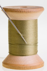 Spool of green thread with a needle