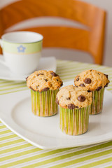 Chocolate chip muffins on white plate and green striped tableclo