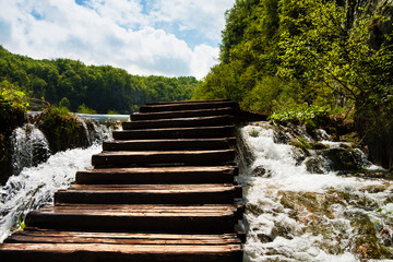 Obraz premium Wet wooden stairs with whitewater and forest