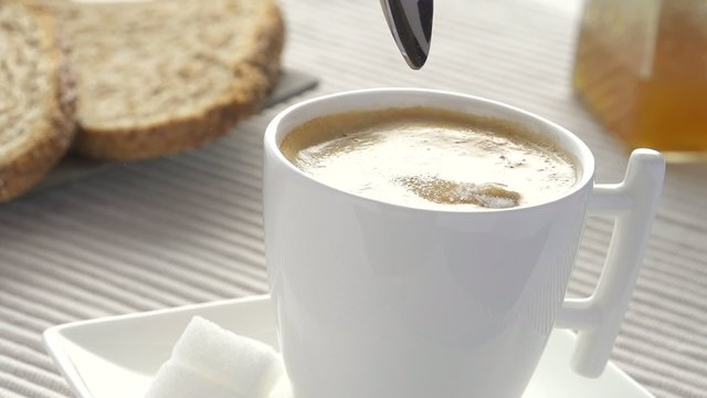 slow motion spoon pouring sugar  in coffee at breakfast table