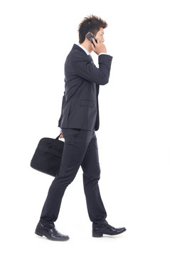 business man walking carrying a suitcase speaking on cellphone