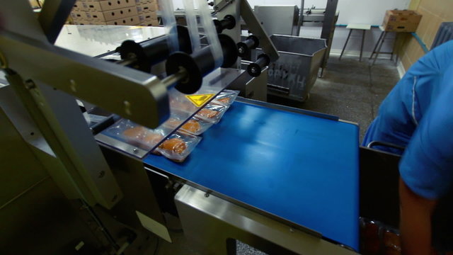 Conveyor with vacuum packed cooked meat