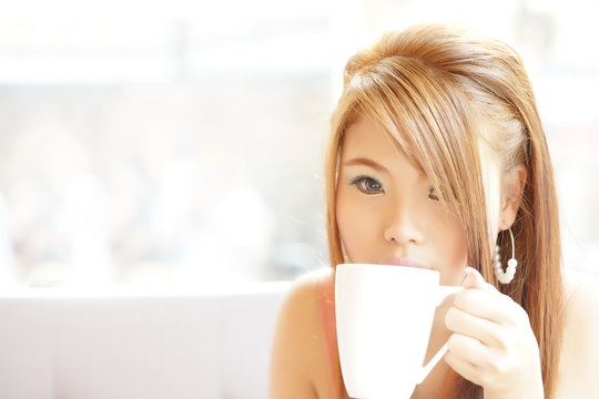 Closeup beautiful woman sitting in cafe holding and drinking cof