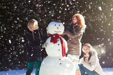 Three girls building a snowman