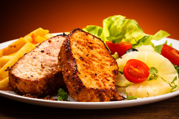 Grilled steaks, French fries and vegetables