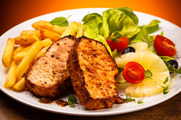 Grilled steaks, French fries and vegetables