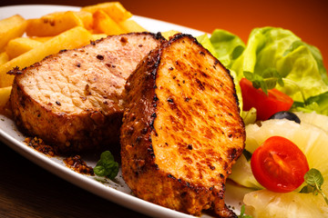 Grilled steaks, French fries and vegetables