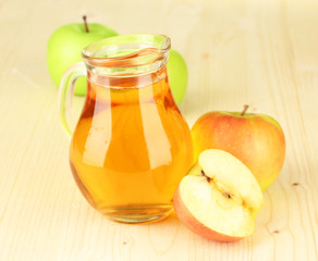 Full jug of apple juice and apple on wooden background