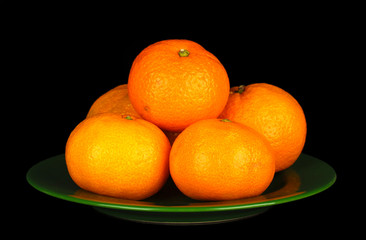 Tasty mandarines  on color plate isolated on black