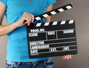 Movie production clapper board in hands on grey background