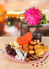 Sweet cookies with valentine card on plate on table in cafe