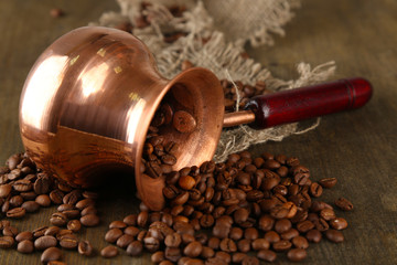 Coffee pot with coffee beans on wooden background