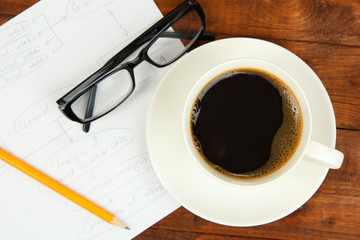 Cup of coffee on worktable covered with documents close up
