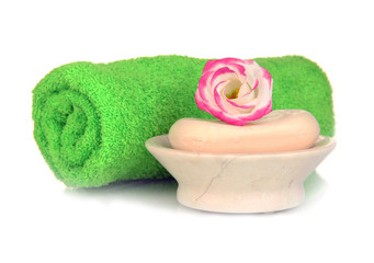 Fototapeta na wymiar Rolled zielony ręcznik, mydła i piękny kwiat wyizolowanych