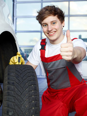Mechanic checks the tread pattern of a winter tire, shows thumb