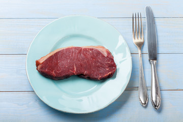 rohes Steak auf einem blauen Teller