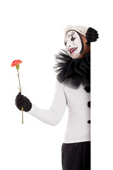 Männlicher Clown mit Blume blickt ums Eck