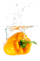 Le poivron orange tombe dans l& 39 eau contre le blanc