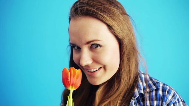 young female model sniffing red tulip. Wind blowing her long hai